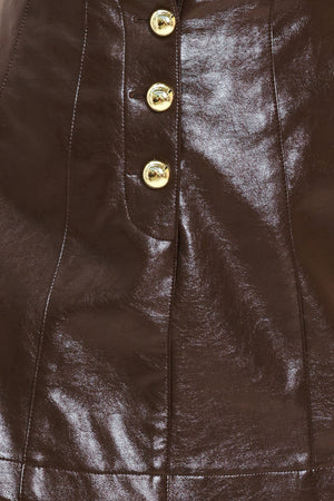 Woman wearing a dark brown faux leather skort with gold buttons on the front | Flying Tomato