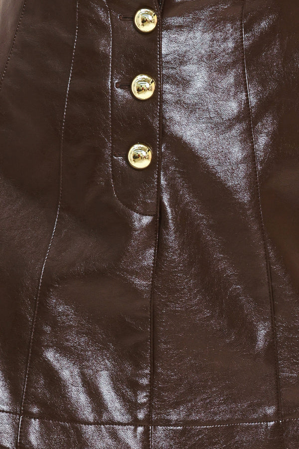 Woman wearing a dark brown faux leather skort with gold buttons on the front | Flying Tomato