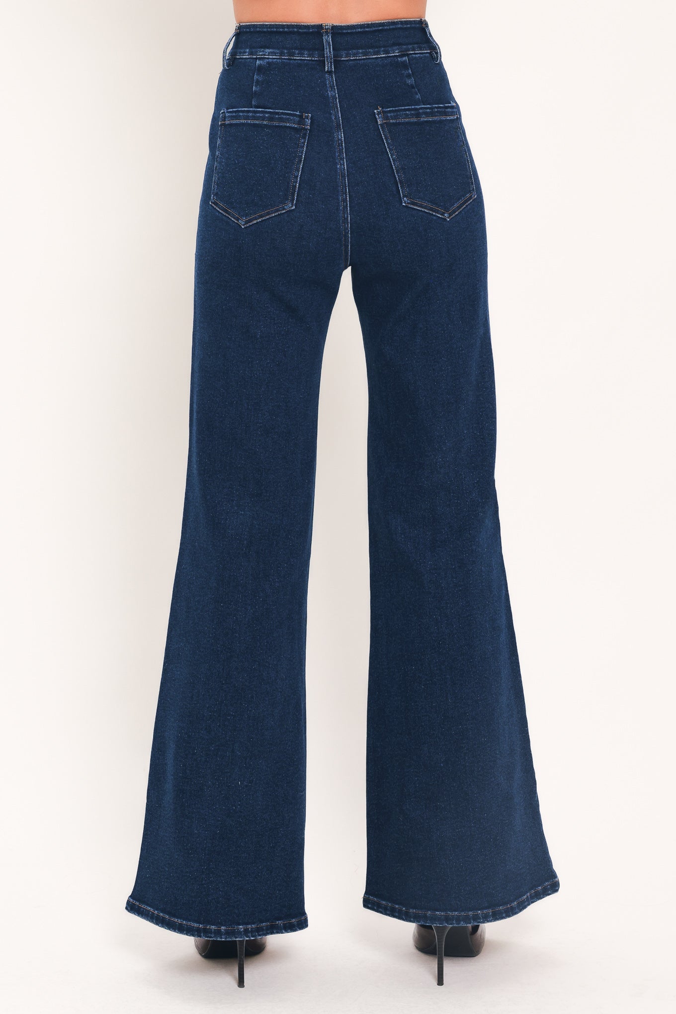 A model wearing dark blue high-waisted flare jeans with distinctive gold-colored contrast stitching running down the center of the legs | Flying Tomato