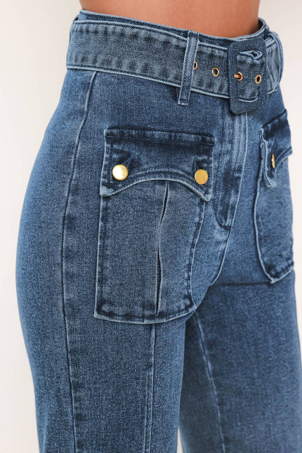 A woman wearing blue high-waisted flare jeans with front flap pockets and gold-tone button details | Flying Tomato