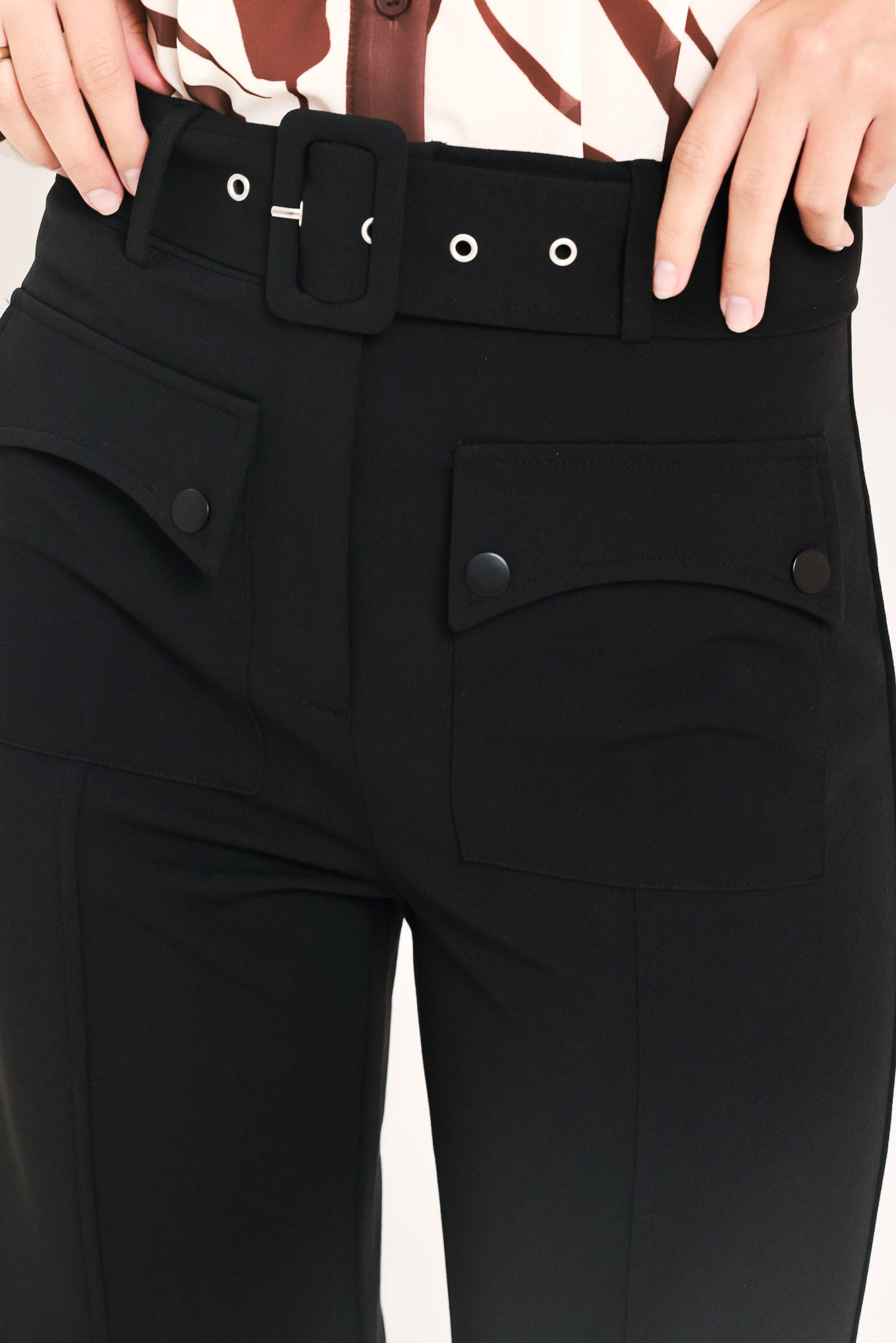 Woman wearing a pair of black pants with a belt and front pockets | Flying Tomato