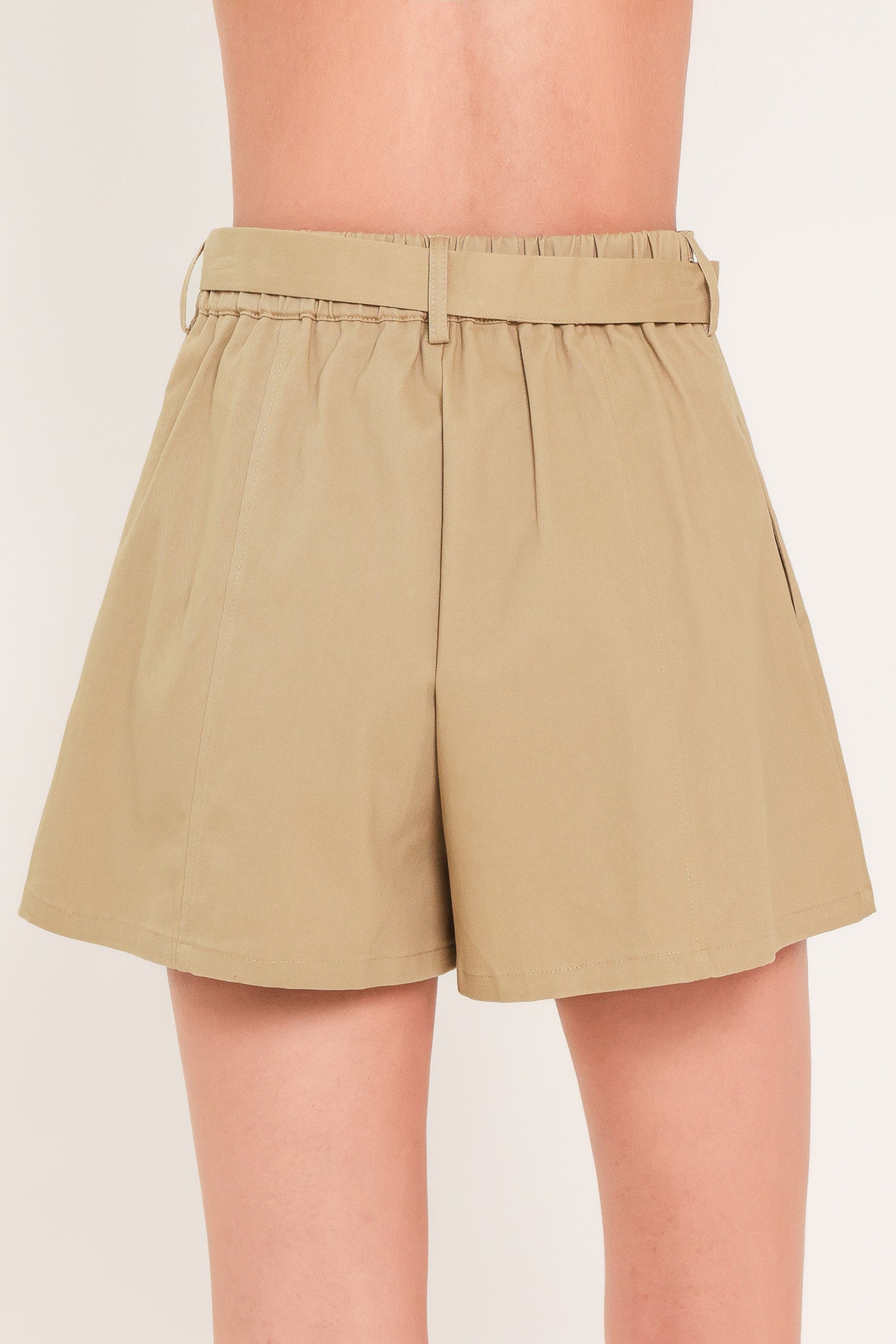 Woman wearing a taupe beige high waisted shorts with a self tie matching belt | Flying Tomato