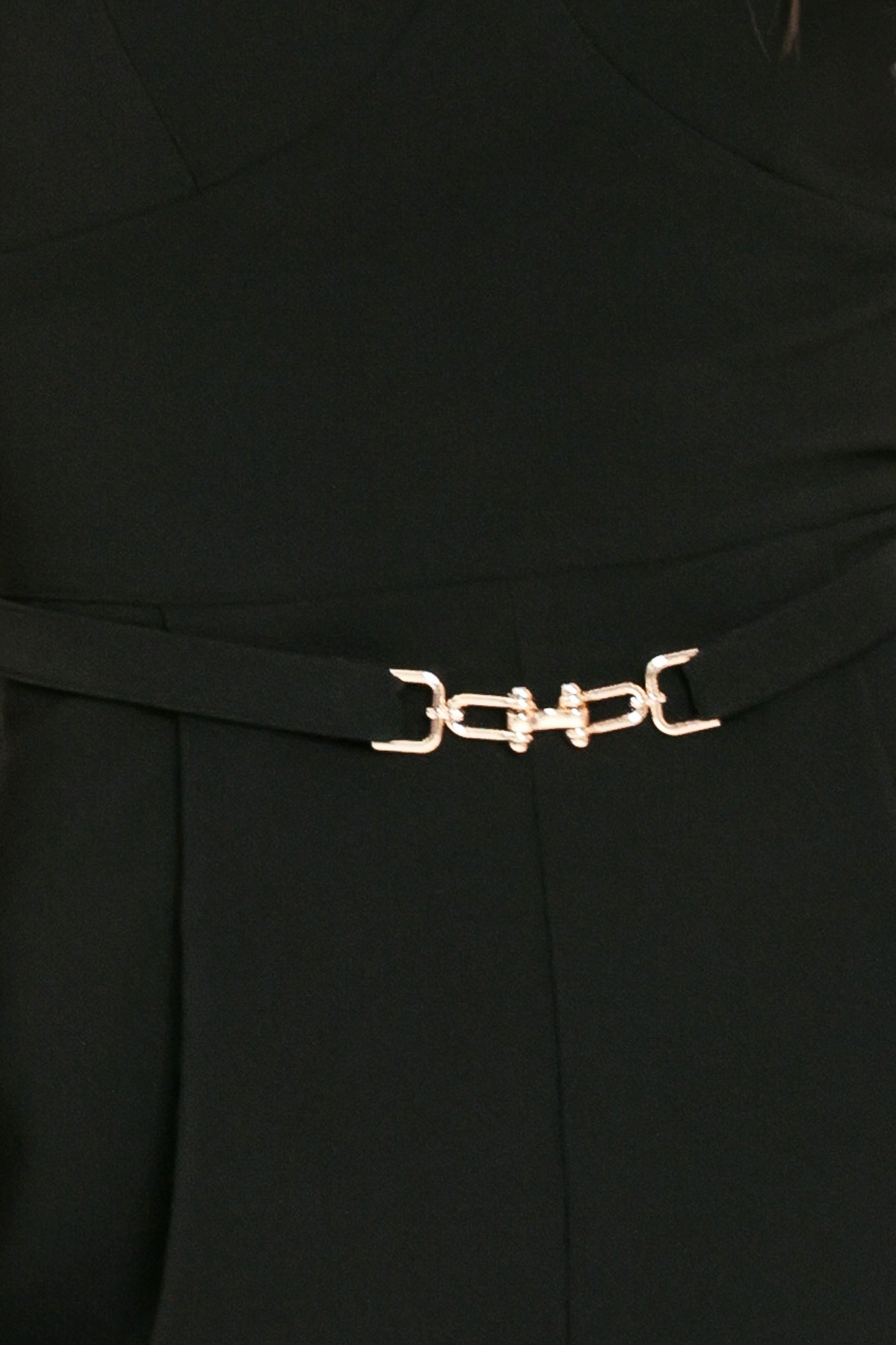 Woman wearing a black romper featuring V neckline, cap sleeve, belt, side pockets and back zipper closure | Flying Tomato