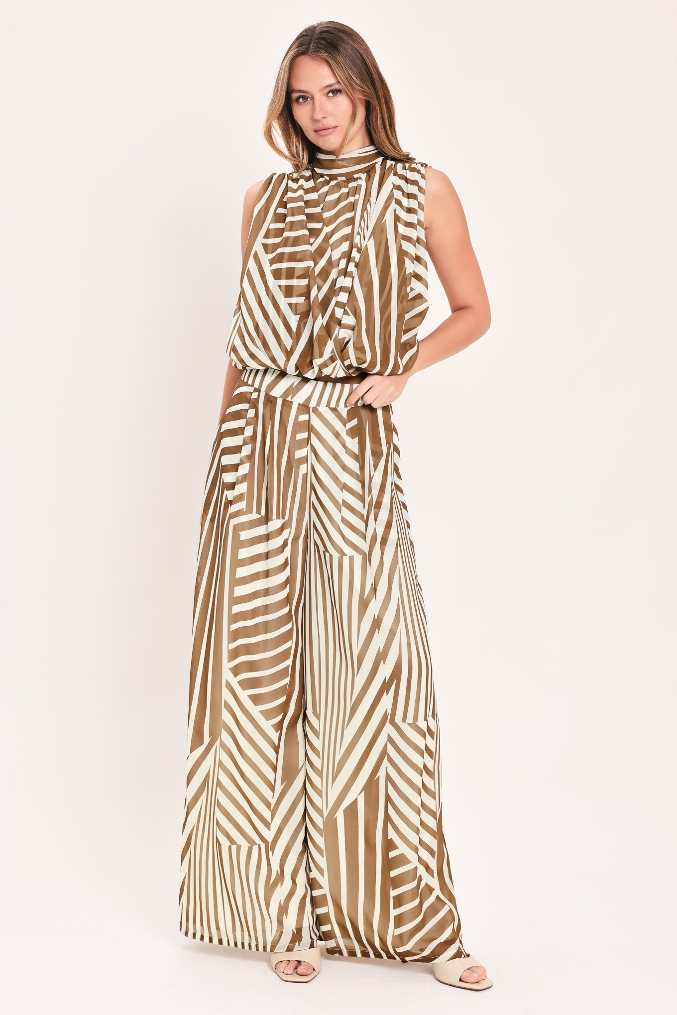 Woman wearing a pair of high waisted flowy wide leg pants with a geometric mocha and white pattern | Flying Tomato
