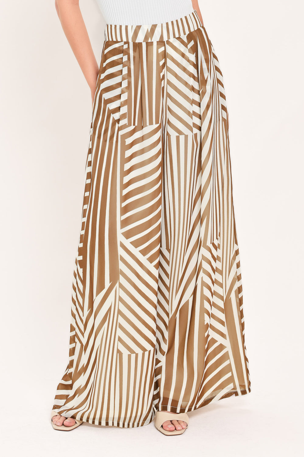 Woman wearing a pair of high waisted flowy wide leg pants with a geometric mocha and white pattern | Flying Tomato