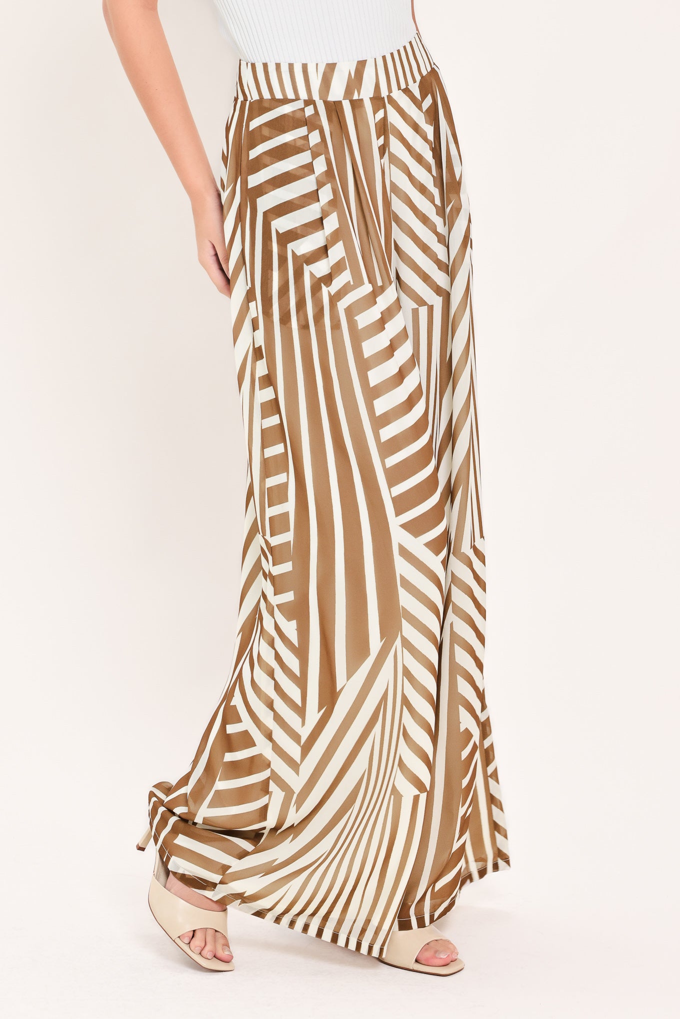 Woman wearing a pair of high waisted flowy wide leg pants with a geometric mocha and white pattern | Flying Tomato