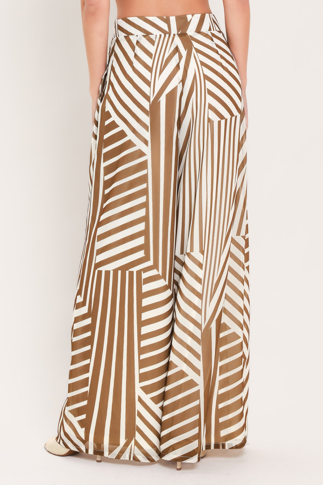 Woman wearing a pair of high waisted flowy wide leg pants with a geometric mocha and white pattern | Flying Tomato