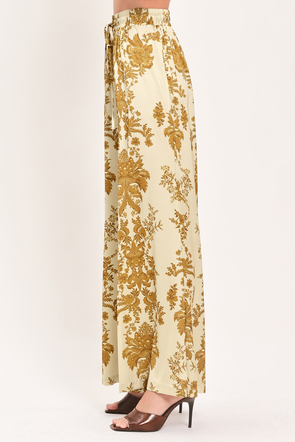 A woman wearing high-waisted, wide-leg pants with a beige base and an ornate gold damask pattern | Flying Tomato