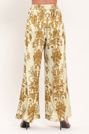 A woman wearing high-waisted, wide-leg pants with a beige base and an ornate gold damask pattern | Flying Tomato