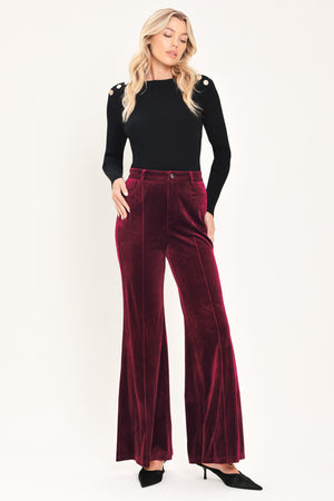 A pair of high-waisted, wide-leg velvet pants in a deep burgundy red, shown on a model | Flying Tomato