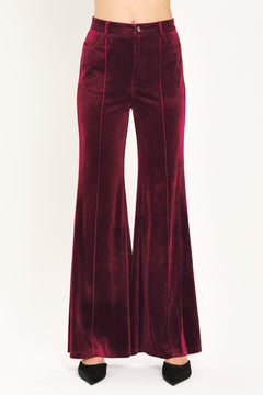 A pair of high-waisted, wide-leg velvet pants in a deep burgundy red, shown on a model | Flying Tomato