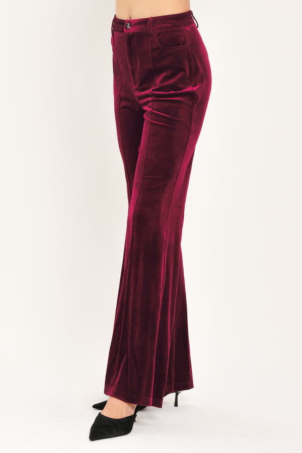 A pair of high-waisted, wide-leg velvet pants in a deep burgundy red, shown on a model | Flying Tomato