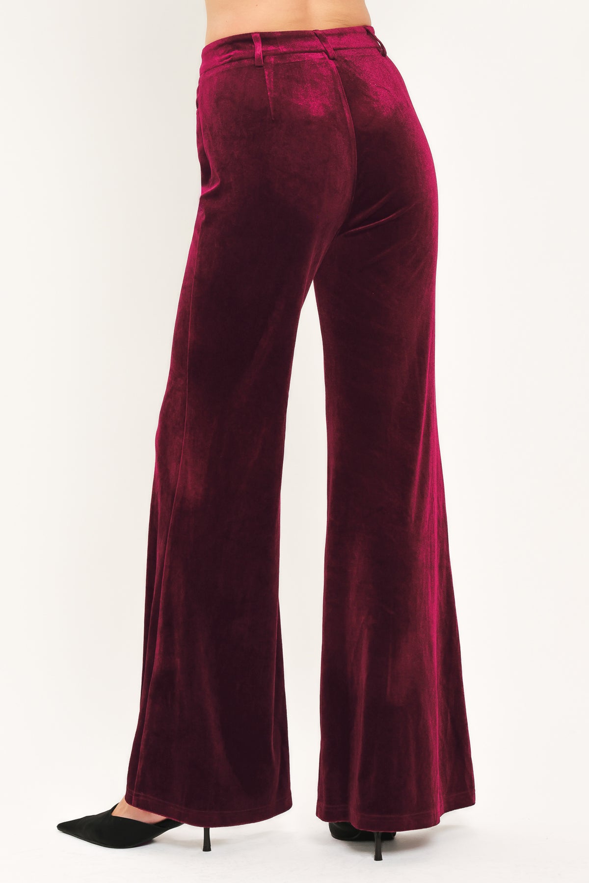 A pair of high-waisted, wide-leg velvet pants in a deep burgundy red, shown on a model | Flying Tomato