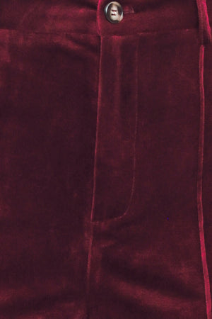 A pair of high-waisted, wide-leg velvet pants in a deep burgundy red, shown on a model | Flying Tomato