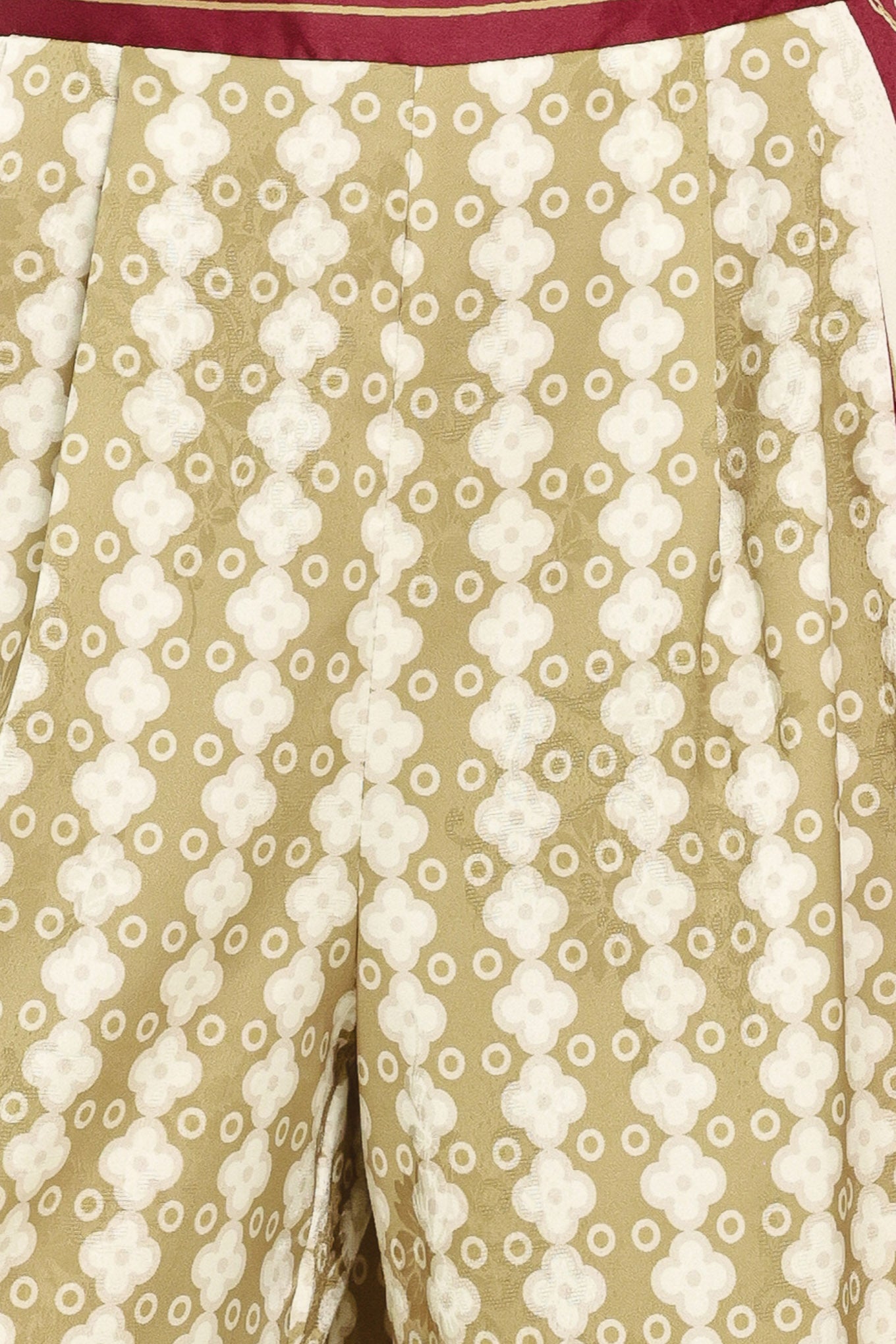 A woman wearing a pair of wide-leg pants with a beige and gold geometric pattern, featuring deep burgundy side panels and a matching patterned hem | Flying Tomato