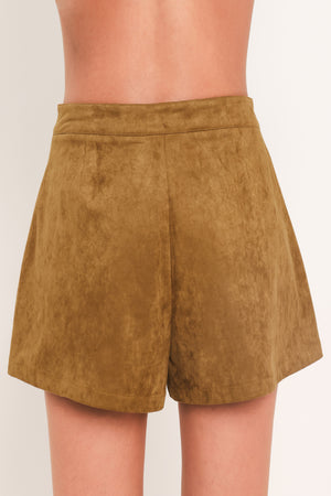 A woman wearing a camel suede mini skort with pleated detailing and lace-up front accents | Flying Tomato