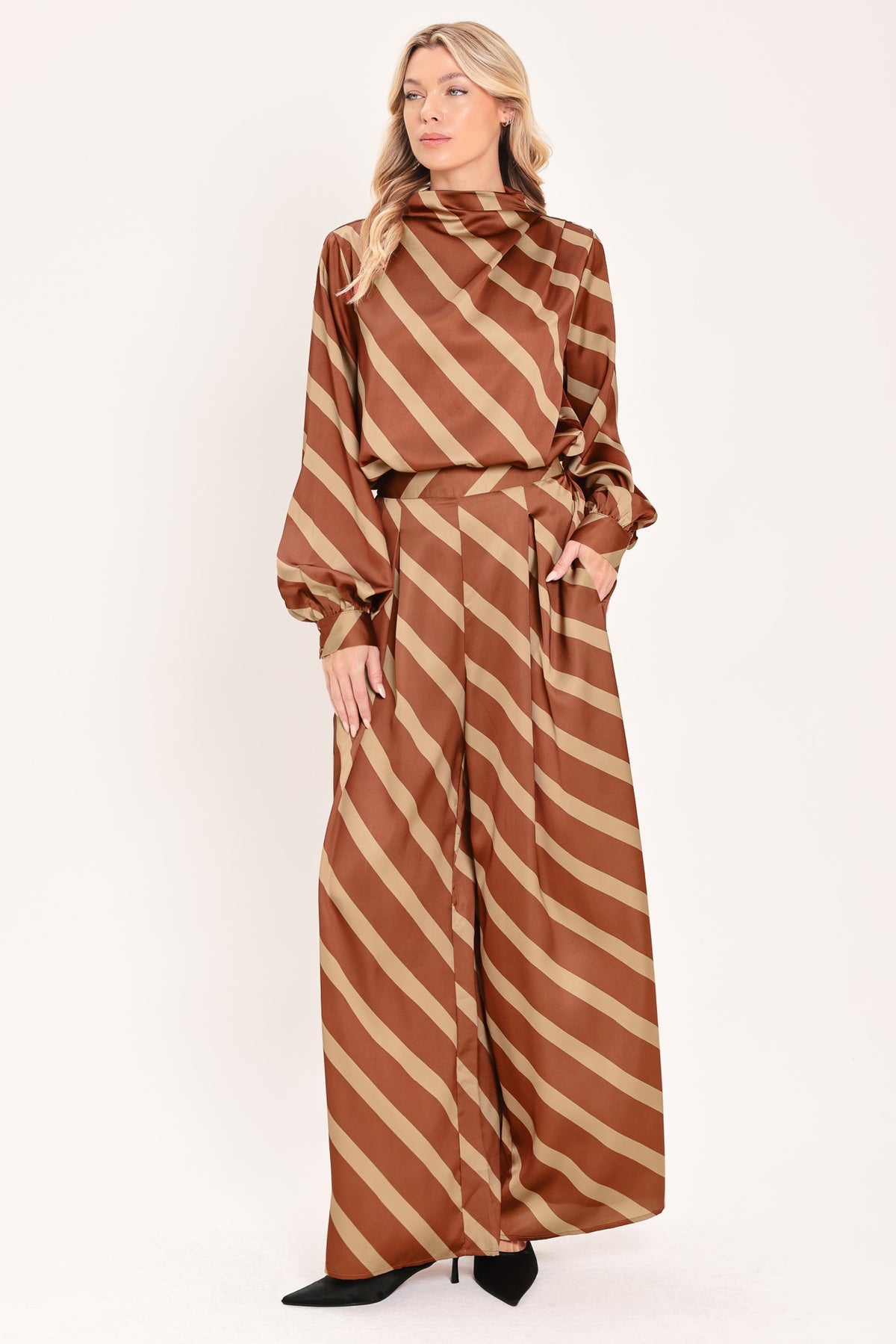 A pair of wide-leg pants with a diagonal striped pattern in rust brown and beige, shown on a model | Flying Tomato