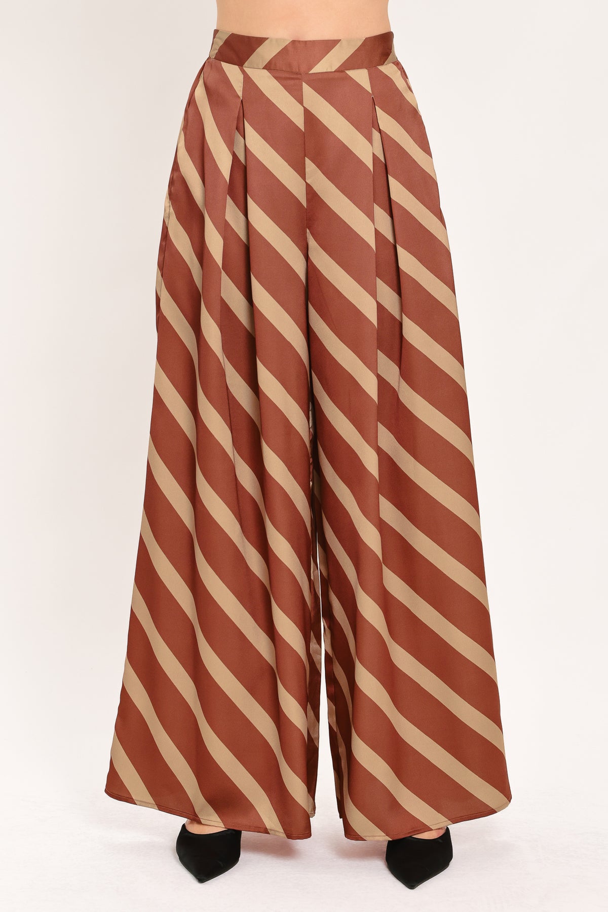 A pair of wide-leg pants with a diagonal striped pattern in rust brown and beige, shown on a model | Flying Tomato