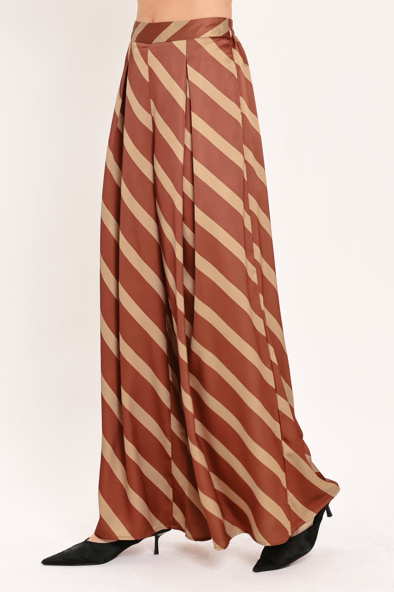 A pair of wide-leg pants with a diagonal striped pattern in rust brown and beige, shown on a model | Flying Tomato