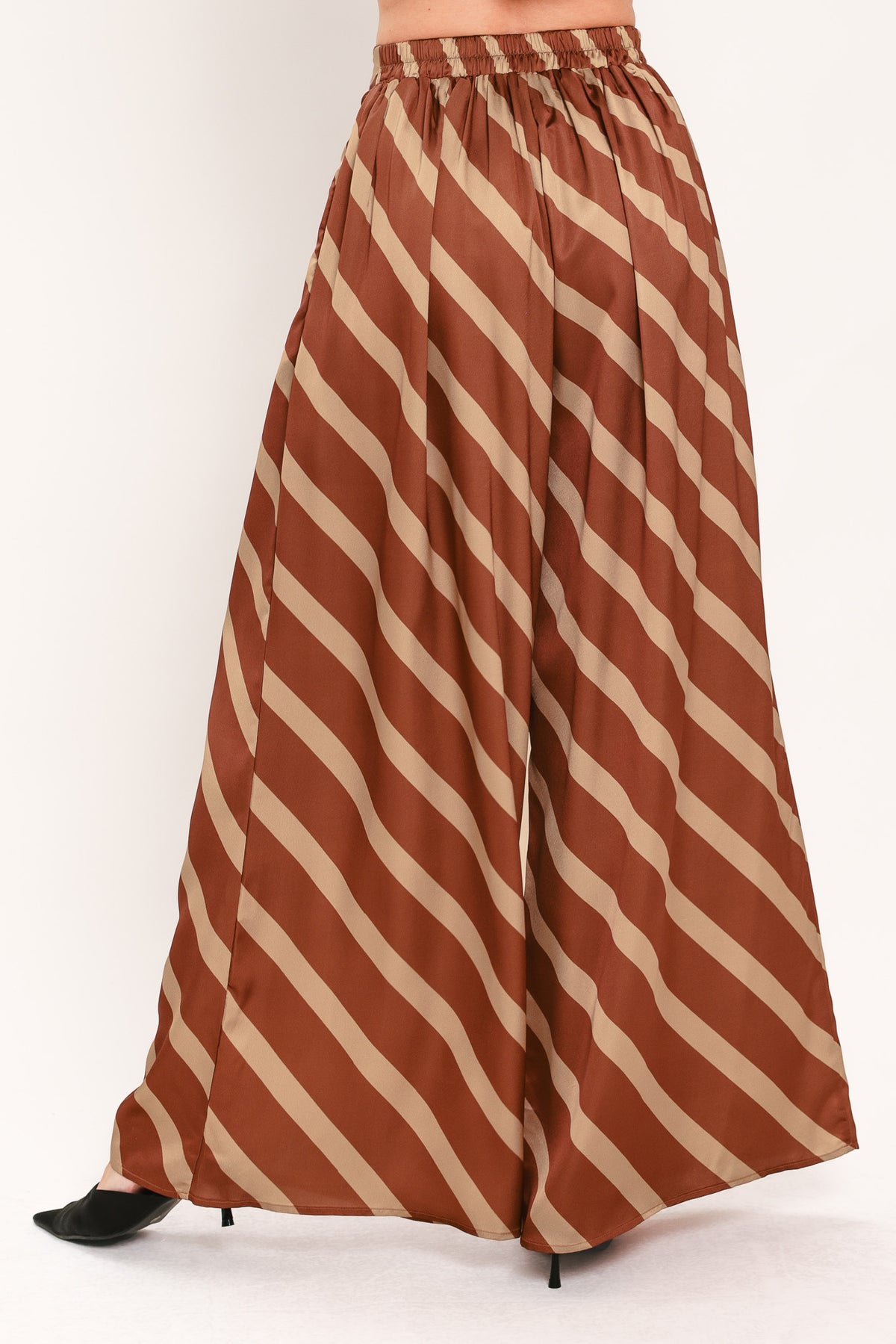 A pair of wide-leg pants with a diagonal striped pattern in rust brown and beige, shown on a model | Flying Tomato