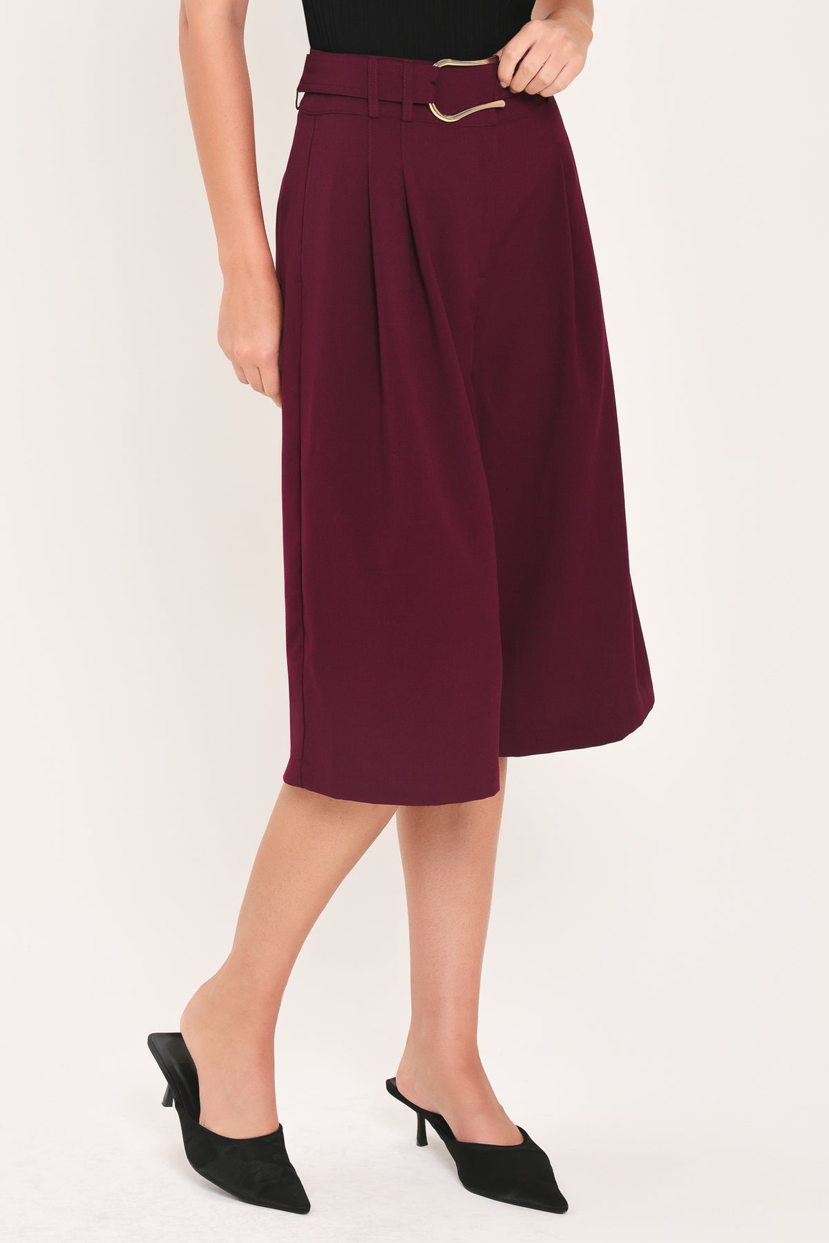A model wearing high-waisted, wide-leg cropped trousers in deep burgundy with pleats and a matching belt | Flying Tomato