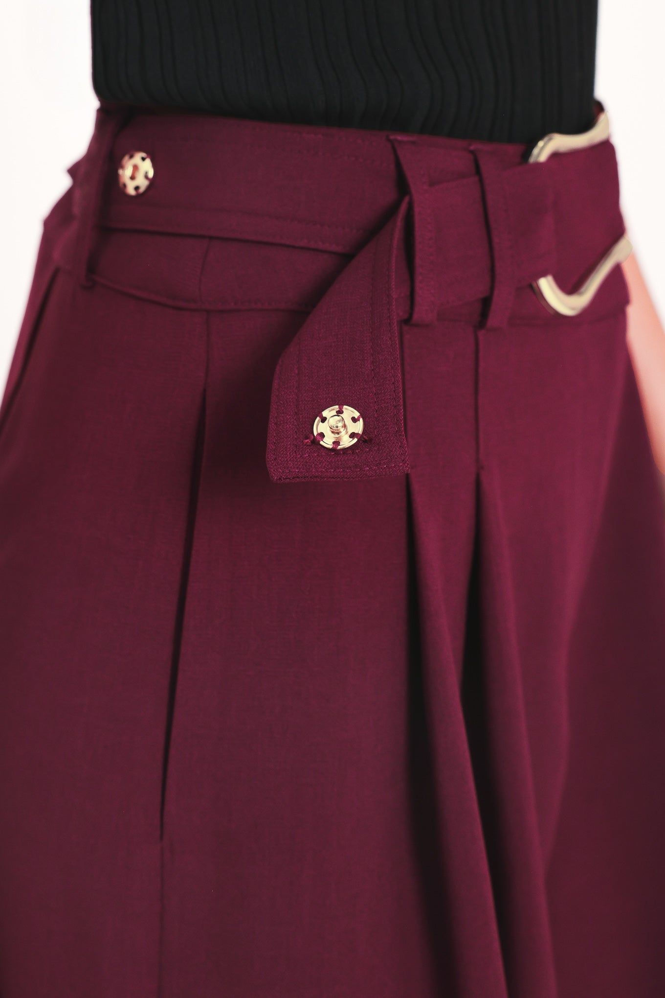 A model wearing high-waisted, wide-leg cropped trousers in deep burgundy with pleats and a matching belt | Flying Tomato