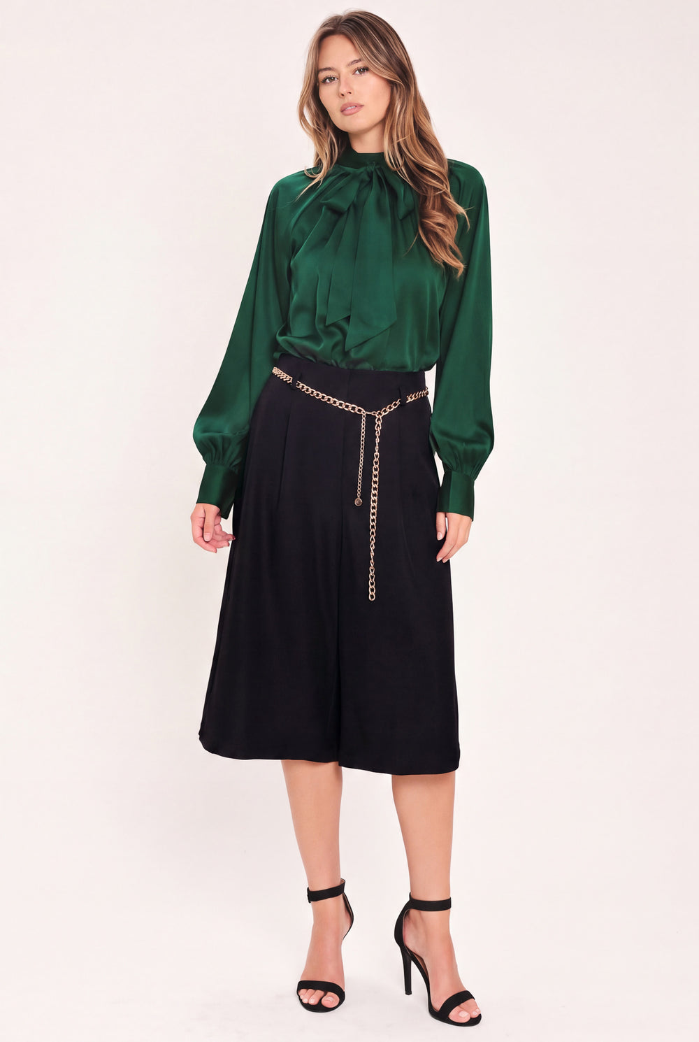 A model wearing a black high-waisted culotta skirt with a gold chain belt detail | Flying Tomato