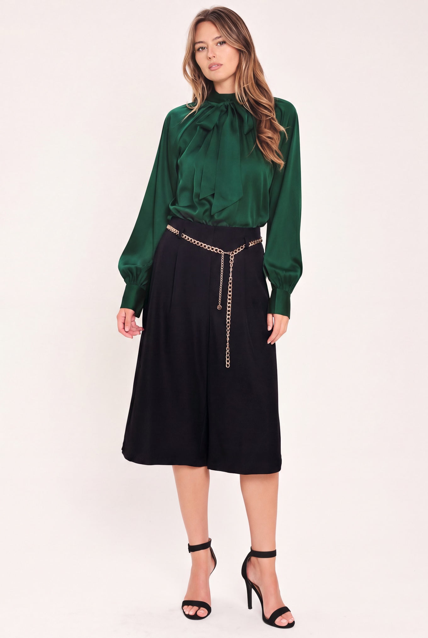 A model wearing a black high-waisted culotta skirt with a gold chain belt detail | Flying Tomato