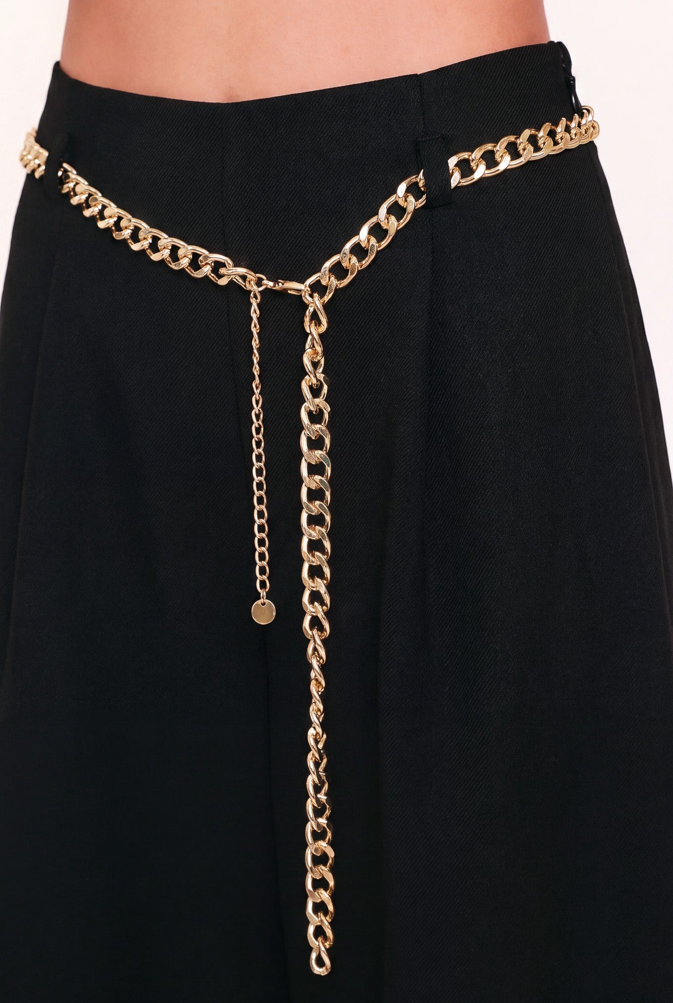 A model wearing a black high-waisted culotta skirt with a gold chain belt detail | Flying Tomato