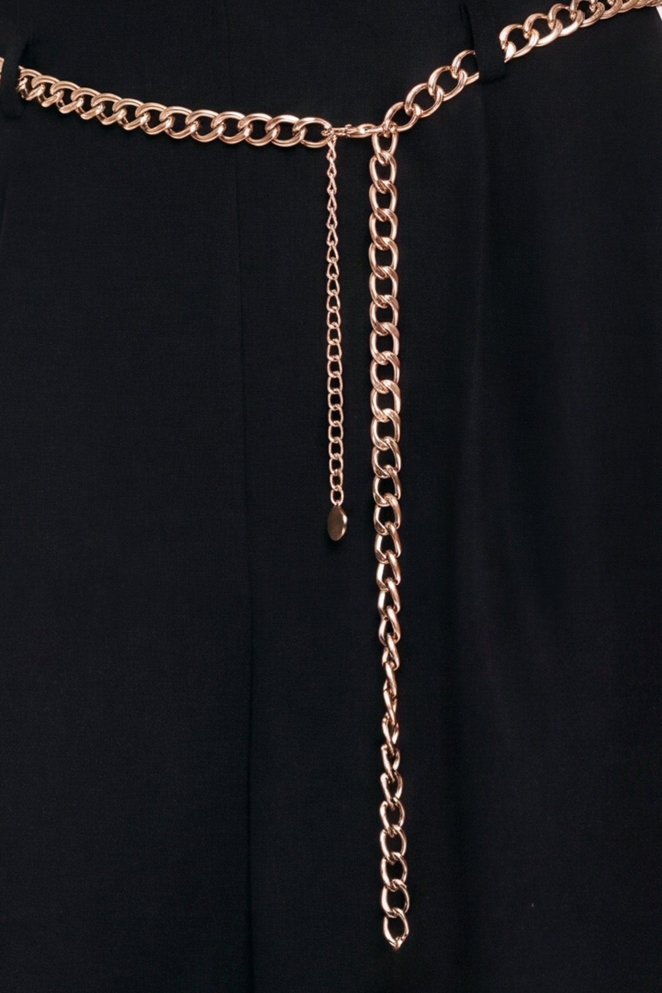 A model wearing a black high-waisted culotta skirt with a gold chain belt detail | Flying Tomato