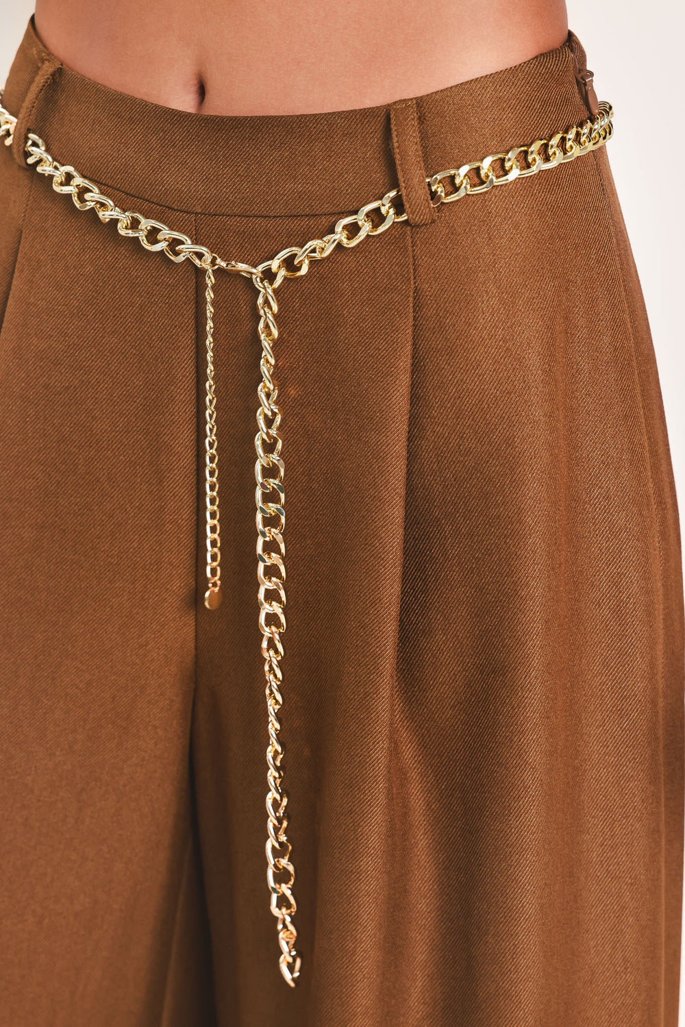 A person wearing high-waisted, wide-leg brown pants with a decorative gold chain belt detail at the waist | Flying Tomato