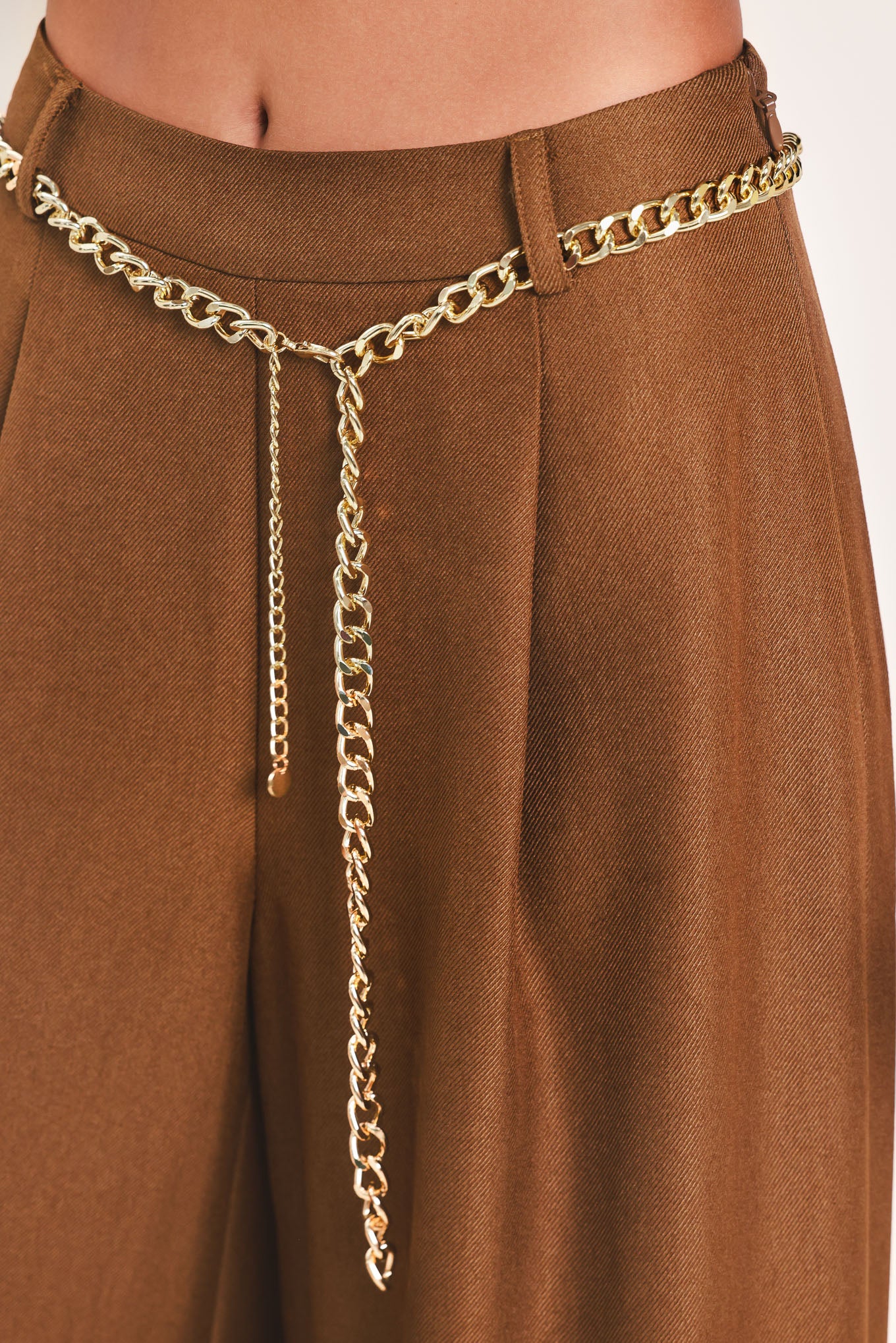 A person wearing high-waisted, wide-leg brown pants with a decorative gold chain belt detail at the waist | Flying Tomato
