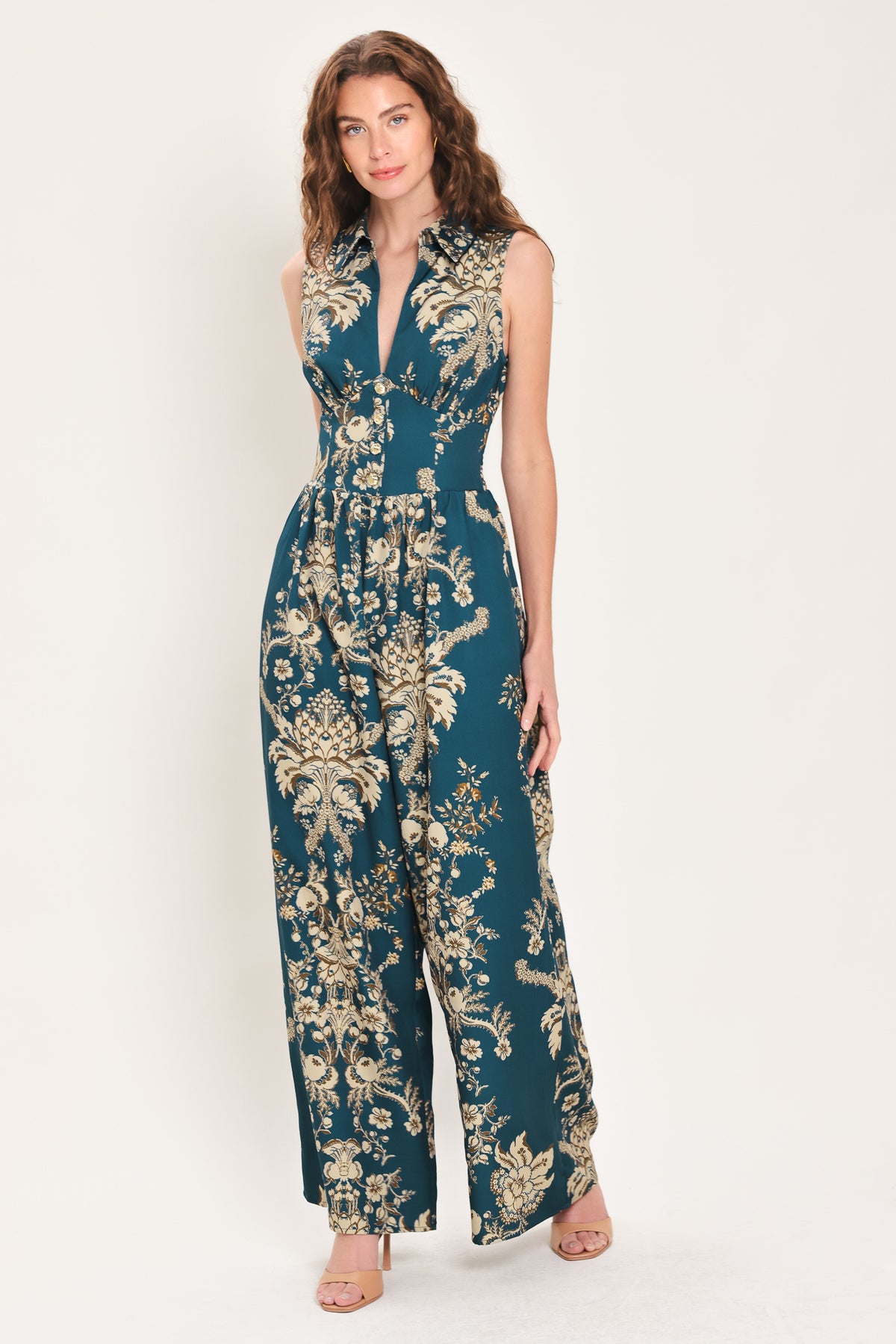 Woman wearing a teal blue jumpsuit with a collar v neckline, and beige baroque print | Flying Tomato