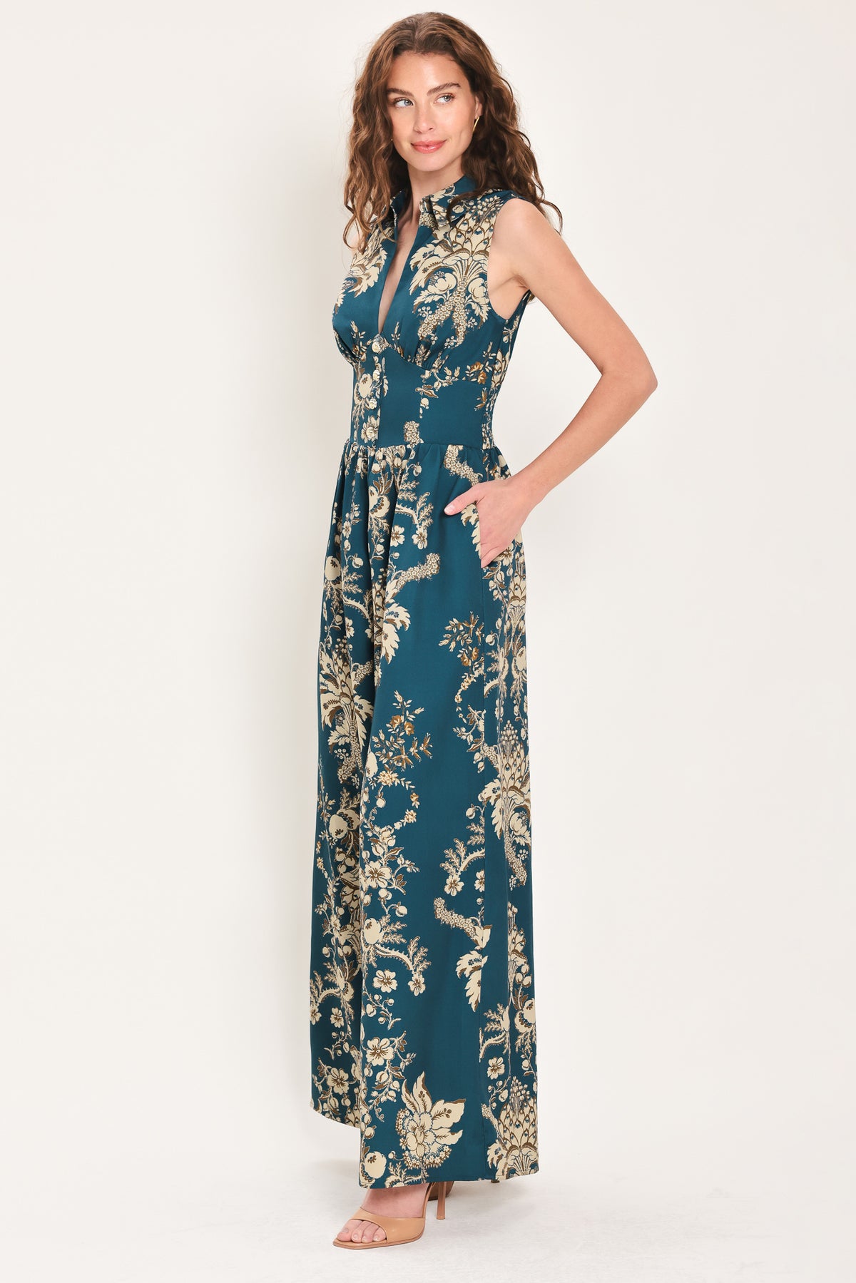 Woman wearing a teal blue jumpsuit with a collar v neckline, and beige baroque print | Flying Tomato
