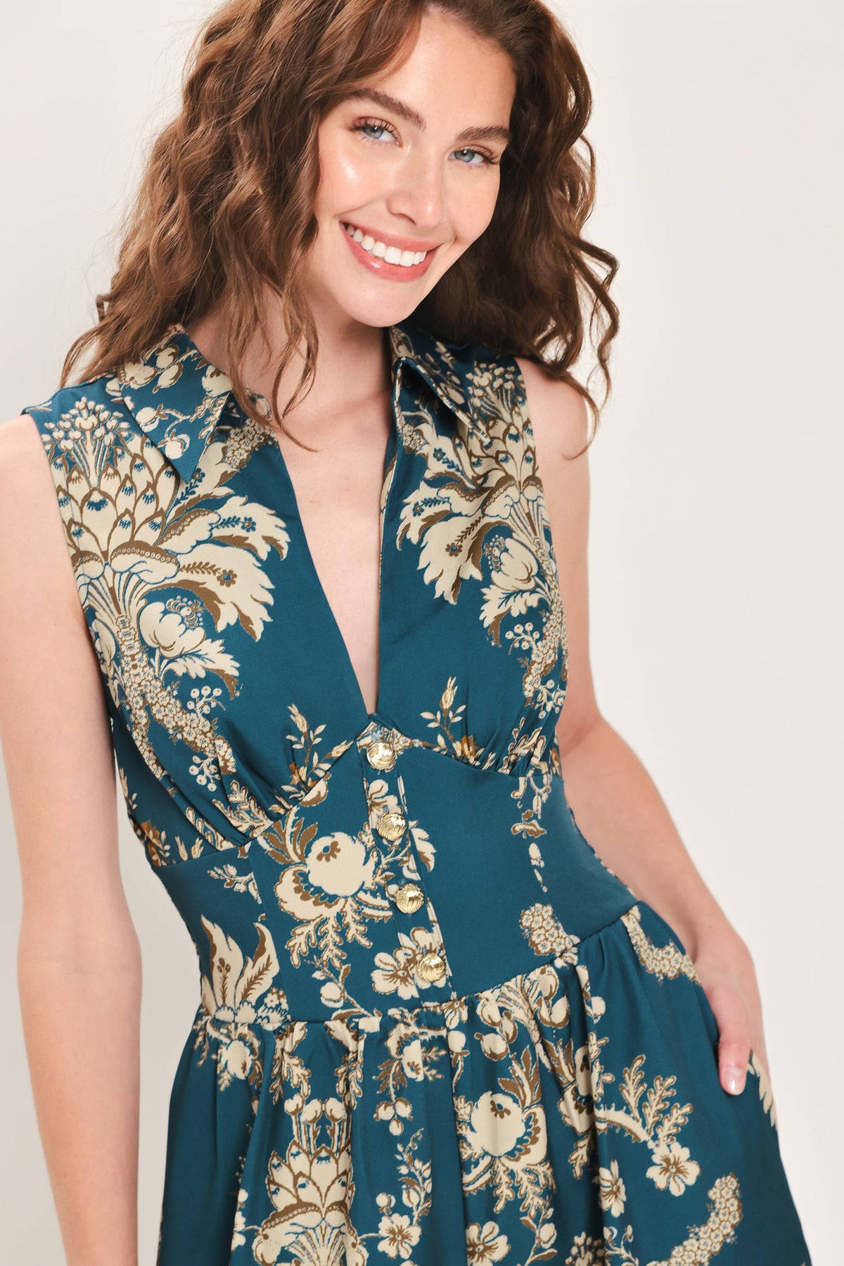 Woman wearing a teal blue jumpsuit with a collar v neckline, and beige baroque print | Flying Tomato