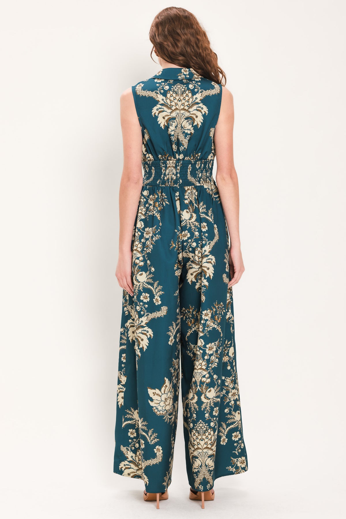 Woman wearing a teal blue jumpsuit with a collar v neckline, and beige baroque print | Flying Tomato
