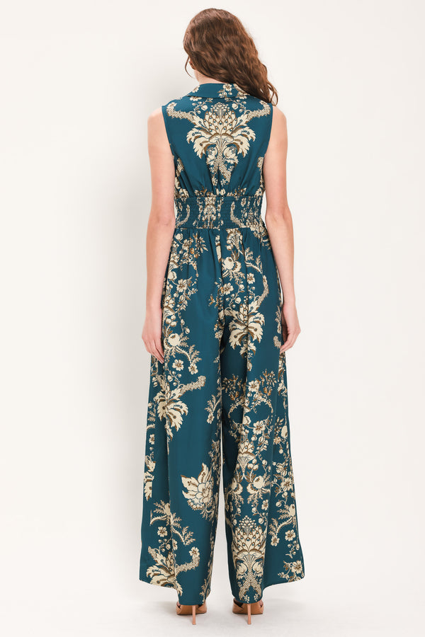 Woman wearing a teal blue jumpsuit with a collar v neckline, and beige baroque print | Flying Tomato