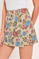 A woman wearing a beige woven jacquard skort with blue and pink flowers and green leaves | Flying Tomato