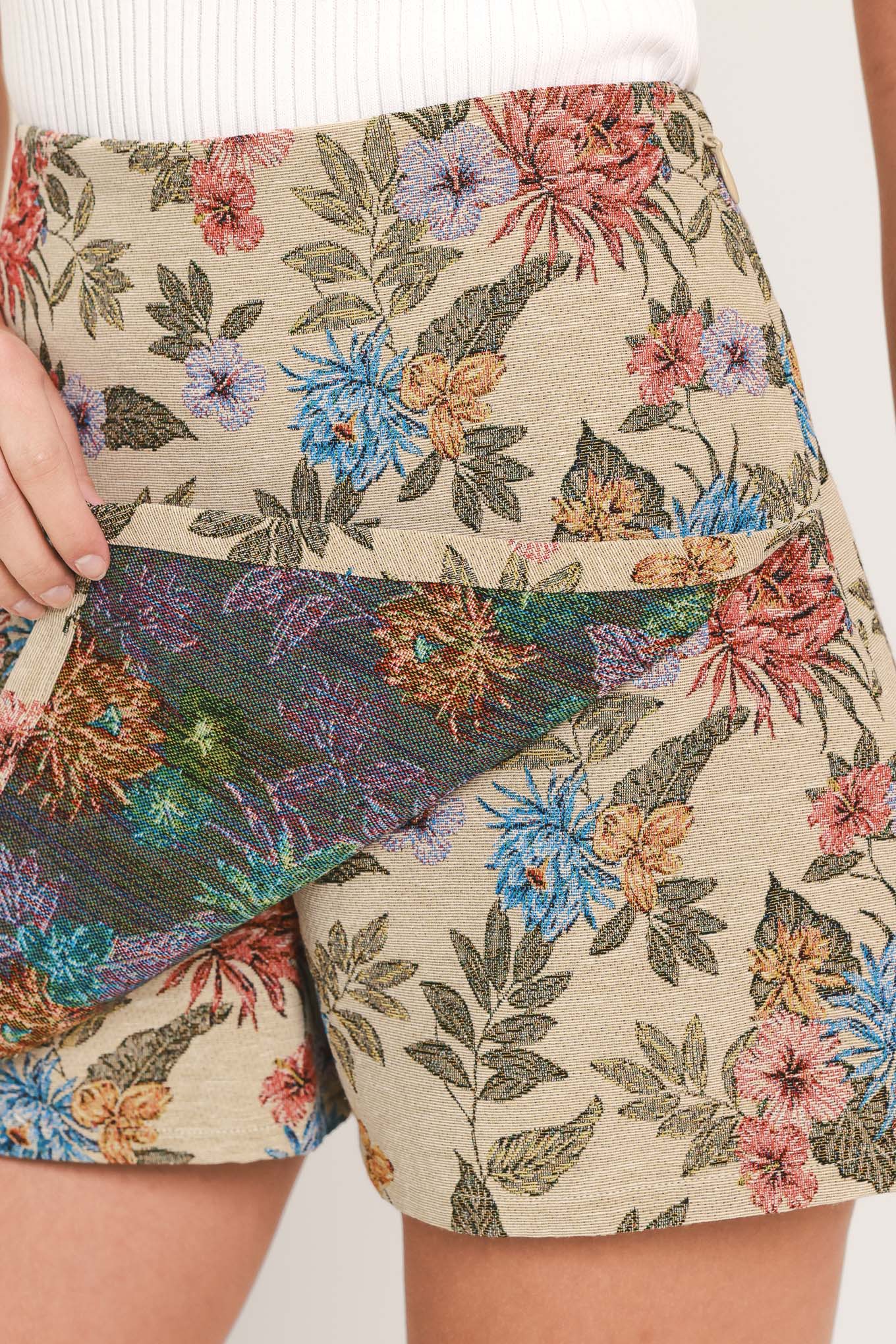 A woman wearing a beige woven jacquard skort with blue and pink flowers and green leaves | Flying Tomato