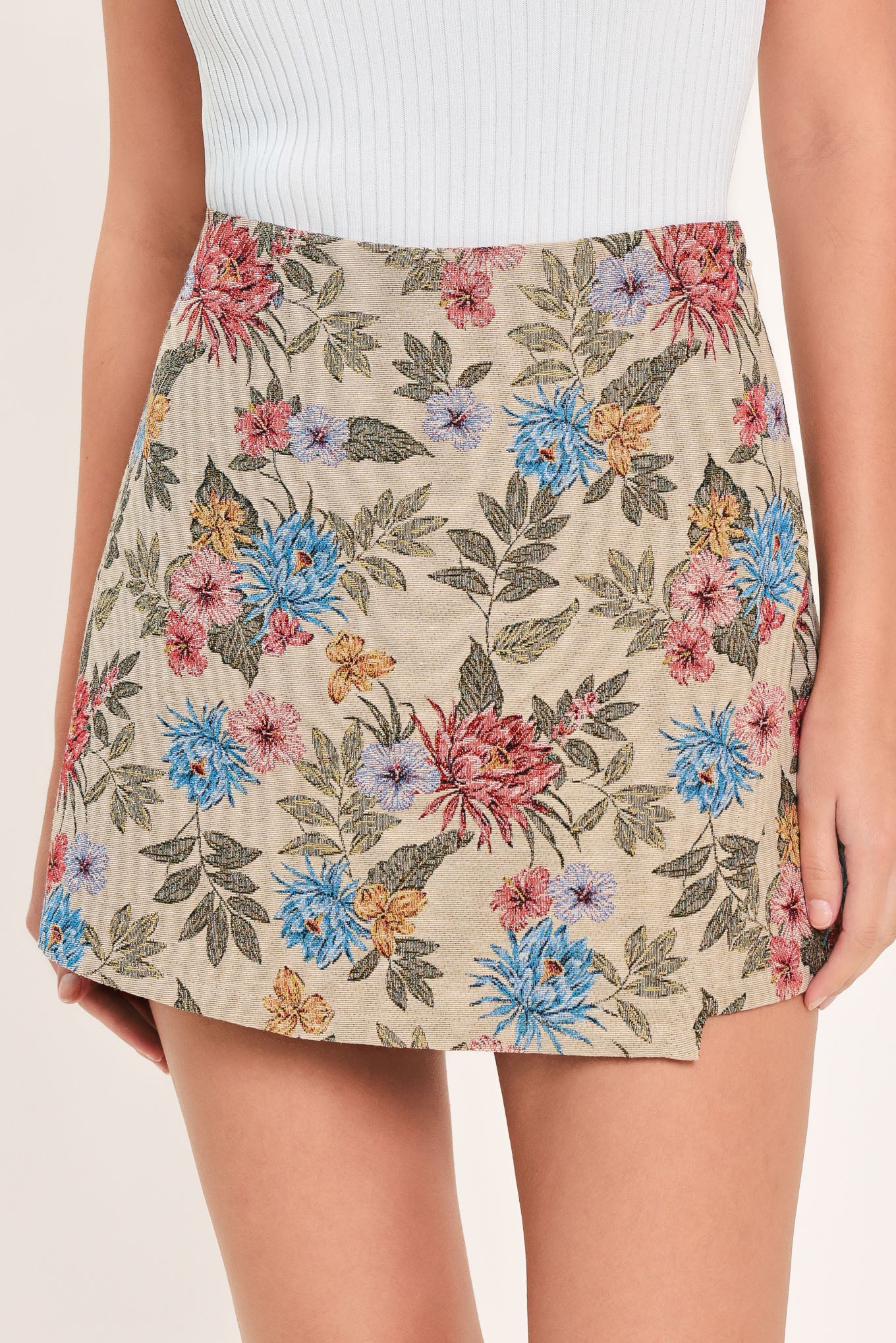 A woman wearing a beige woven jacquard skort with blue and pink flowers and green leaves | Flying Tomato