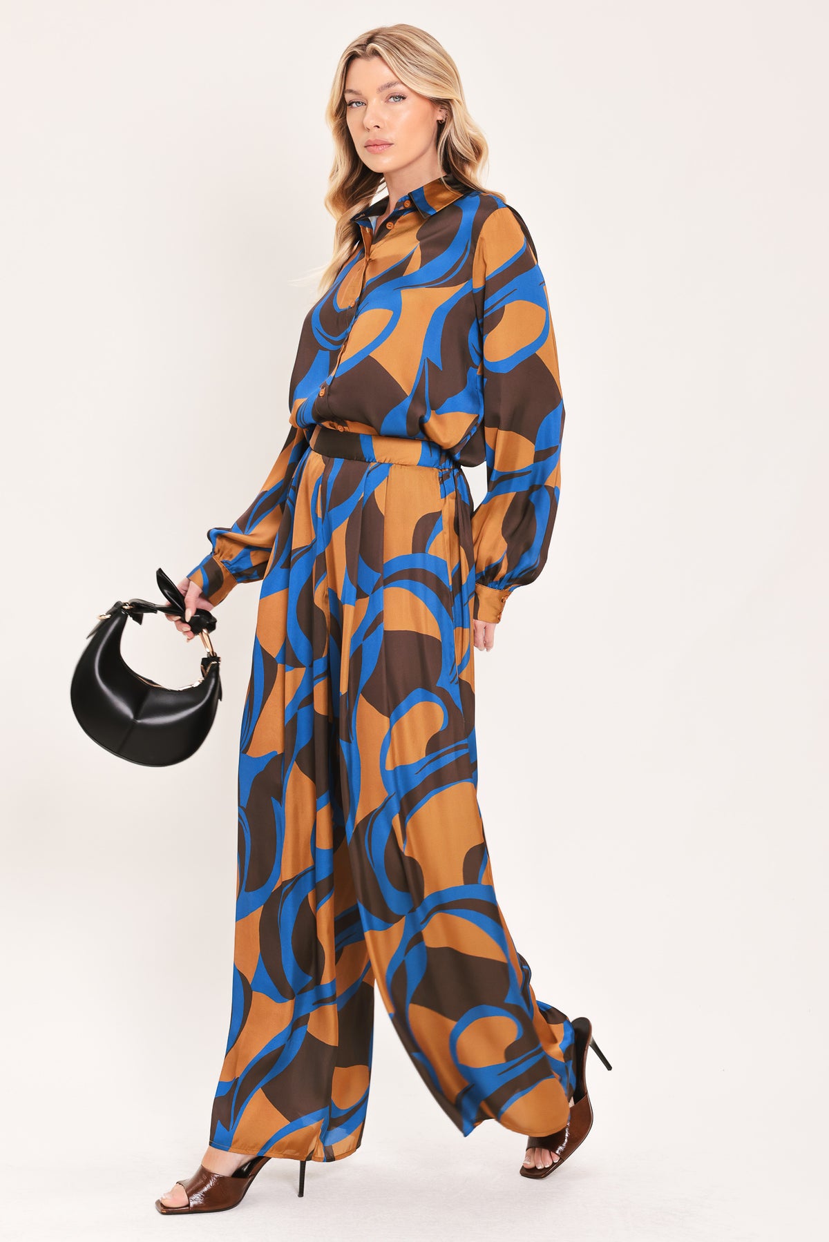 A woman modeling wide-leg pants with a bold abstract swirl pattern in brown, blue, and black | Flying Tomato