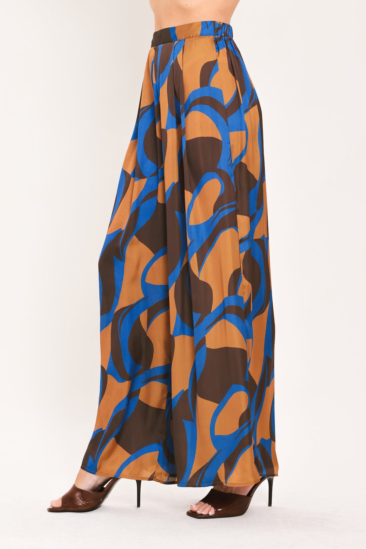 A woman modeling wide-leg pants with a bold abstract swirl pattern in brown, blue, and black | Flying Tomato