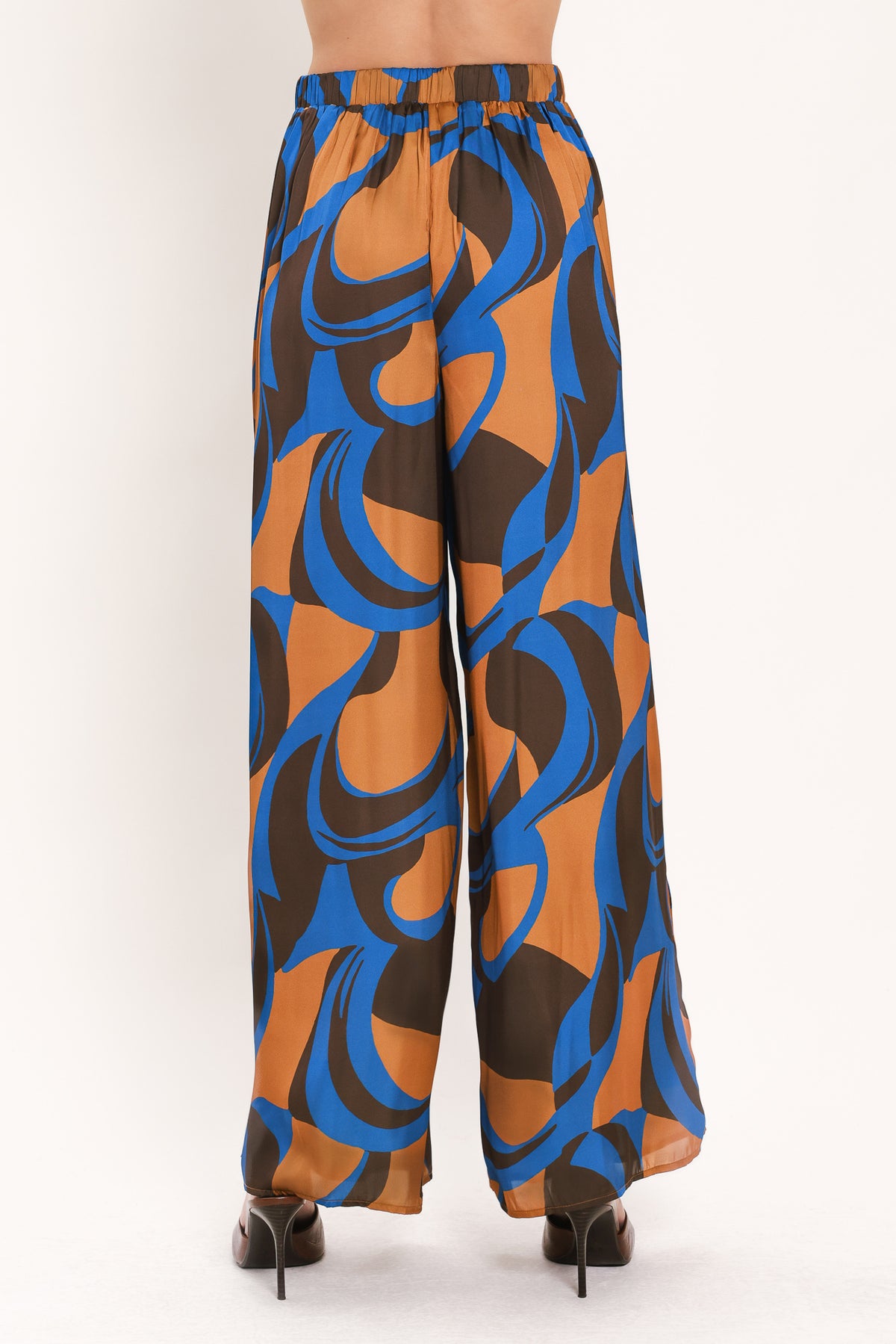 A woman modeling wide-leg pants with a bold abstract swirl pattern in brown, blue, and black | Flying Tomato
