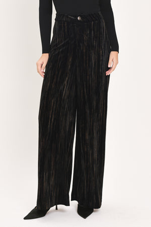 A model wearing high-waisted, wide-leg black pleated velvet trousers with a button waistband | Flying Tomato