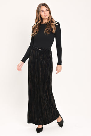 A model wearing high-waisted, wide-leg black pleated velvet trousers with a button waistband | Flying Tomato