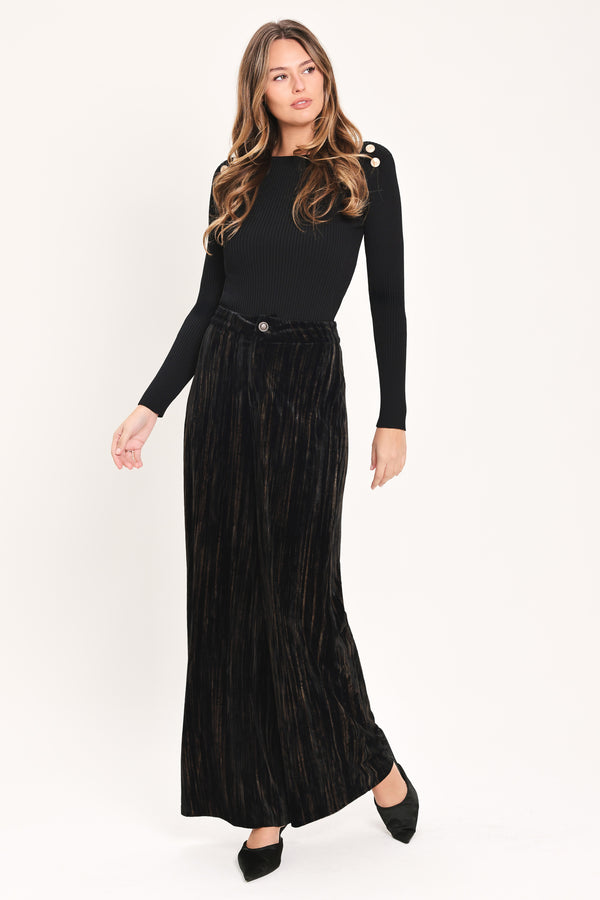 A model wearing high-waisted, wide-leg black pleated velvet trousers with a button waistband | Flying Tomato