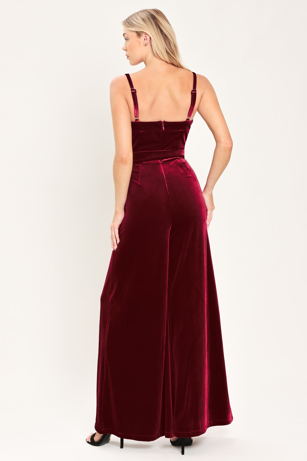 Woman wearing a sleeveless, square-neck red velvet jumpsuit with a matching belt | Flying Tomato