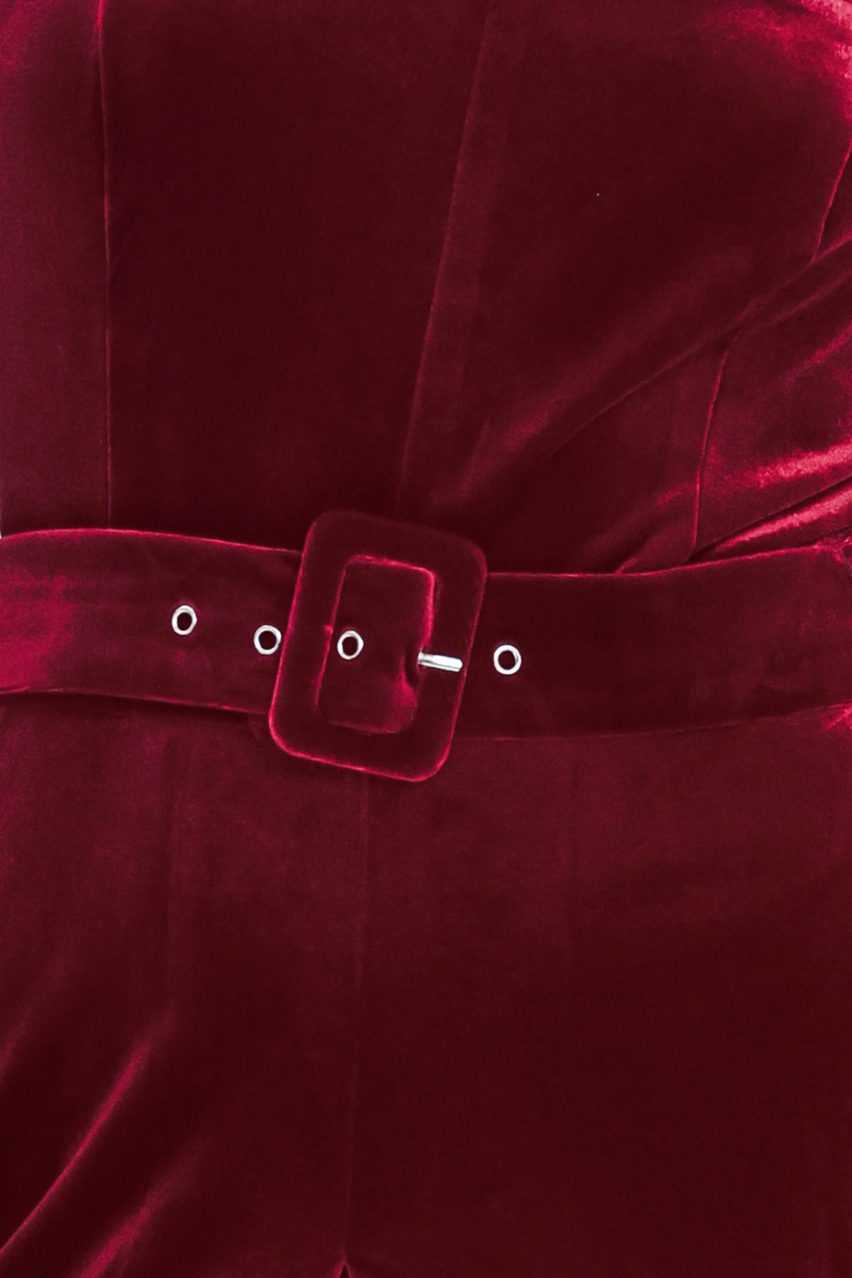 Woman wearing a sleeveless, square-neck red velvet jumpsuit with a matching belt | Flying Tomato