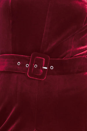 Woman wearing a sleeveless, square-neck red velvet jumpsuit with a matching belt | Flying Tomato