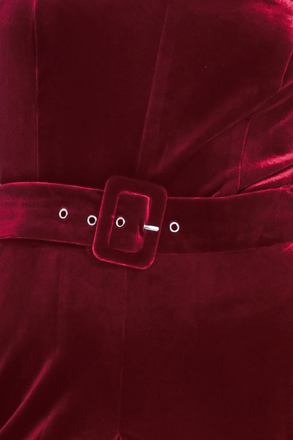 Woman wearing a sleeveless, square-neck red velvet jumpsuit with a matching belt | Flying Tomato